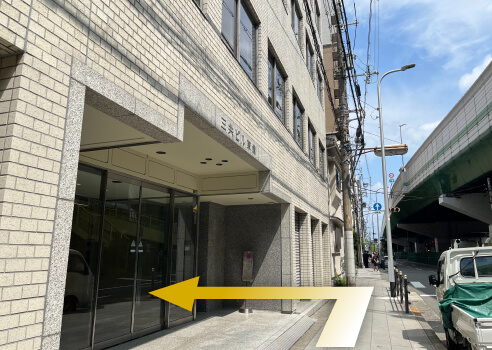 6.「三共ビル東館」の看板をこえて直進すると、ビルの入り口があります。エレベーターで、５階までお越しください。